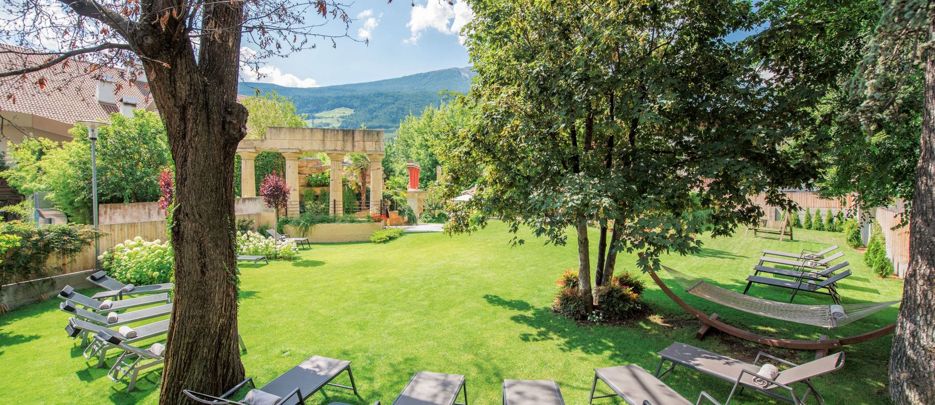 Liegewiese und Garten im Hotel Vier Jahreszeiten in Schlanders, Südtirol, mit Relaxliegen und Blick auf die Berge Liegewiese und Garten im Hotel Vier Jahreszeiten in Schlanders, Südtirol, mit Relaxliegen und Blick auf die Berge